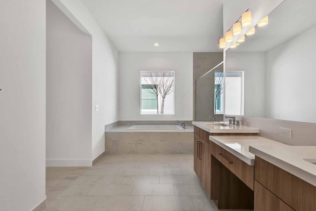 bathroom featuring a relaxing tiled tub and vanity