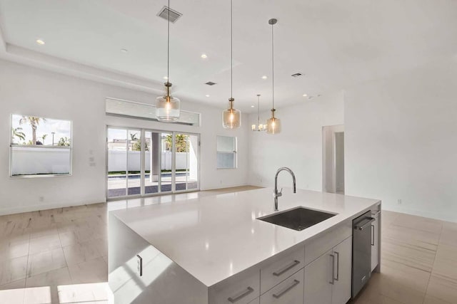 kitchen featuring sink, light tile patterned floors, decorative light fixtures, stainless steel dishwasher, and a large island with sink