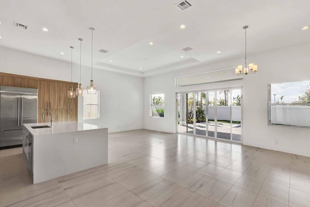 kitchen featuring decorative light fixtures, stainless steel built in fridge, sink, and a large island