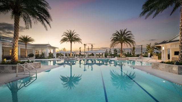 pool at dusk with a patio area