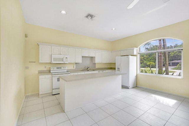 kitchen with a center island, white appliances, white cabinetry, sink, and light tile patterned flooring