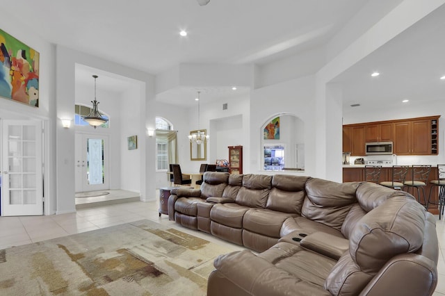 living room with a chandelier, a towering ceiling, and light tile patterned floors