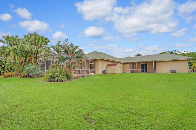 back of property with glass enclosure, a yard, and a storage unit