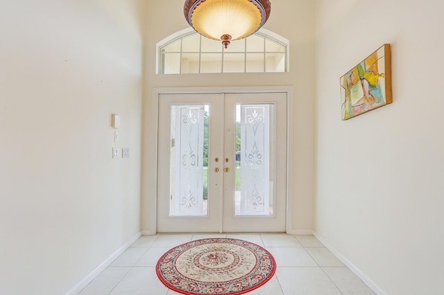 entryway with light tile patterned flooring, a high ceiling, and french doors