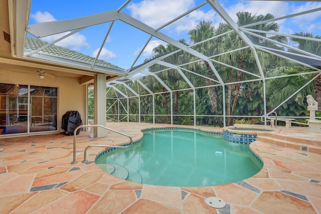 view of pool featuring glass enclosure, an in ground hot tub, ceiling fan, and a patio