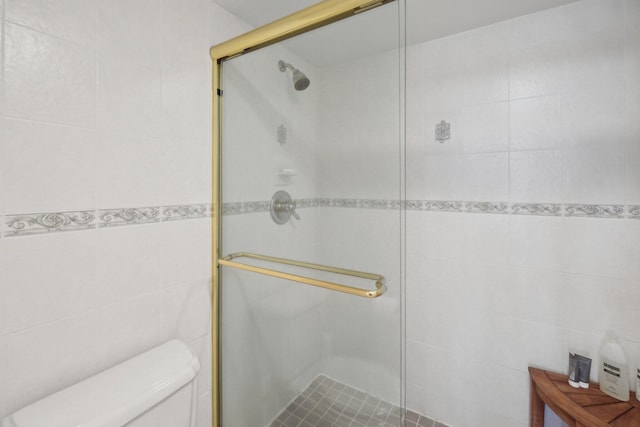 bathroom with an enclosed shower, tile walls, and toilet