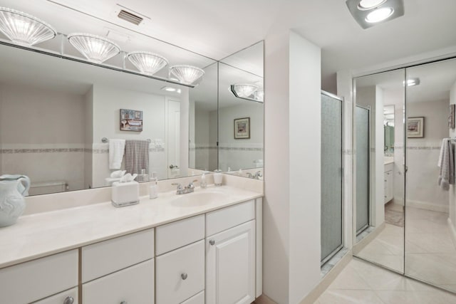 bathroom with tile patterned flooring, a shower with door, toilet, and vanity