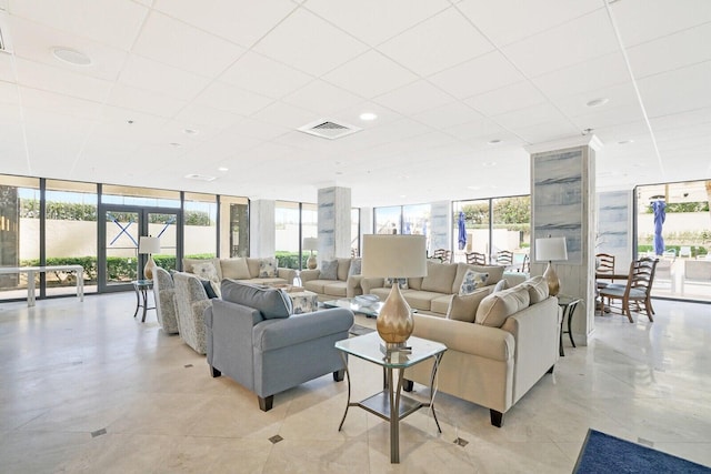 living room with a wall of windows, a drop ceiling, and light tile patterned floors