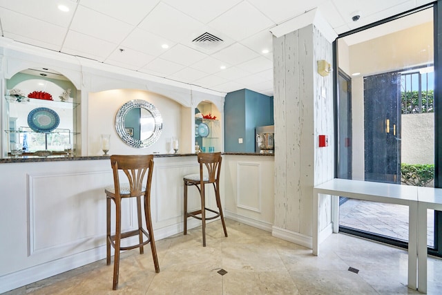 kitchen with a paneled ceiling, dark stone counters, and a wealth of natural light