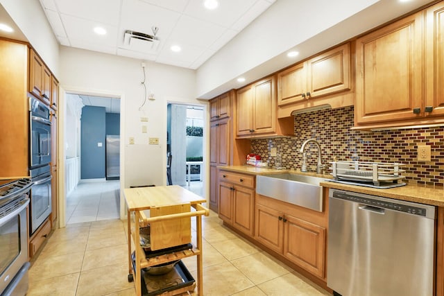 kitchen featuring light tile patterned floors, stainless steel appliances, decorative backsplash, and sink