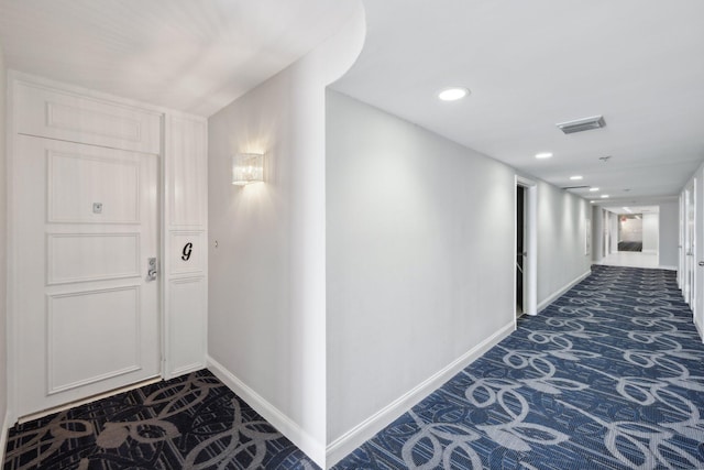 hall with dark colored carpet