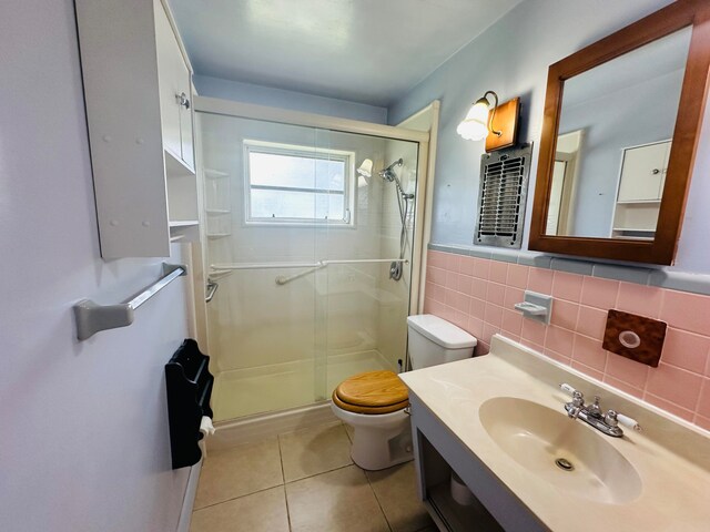 bathroom with toilet, tile patterned flooring, a shower with door, vanity, and tasteful backsplash