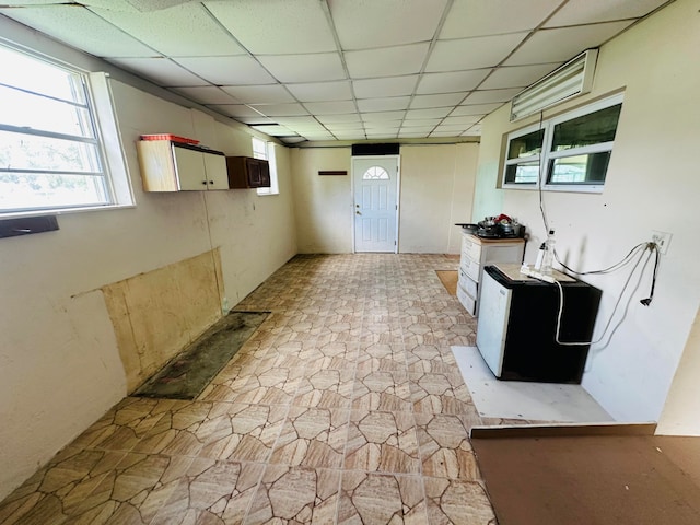 interior space with a paneled ceiling and fridge