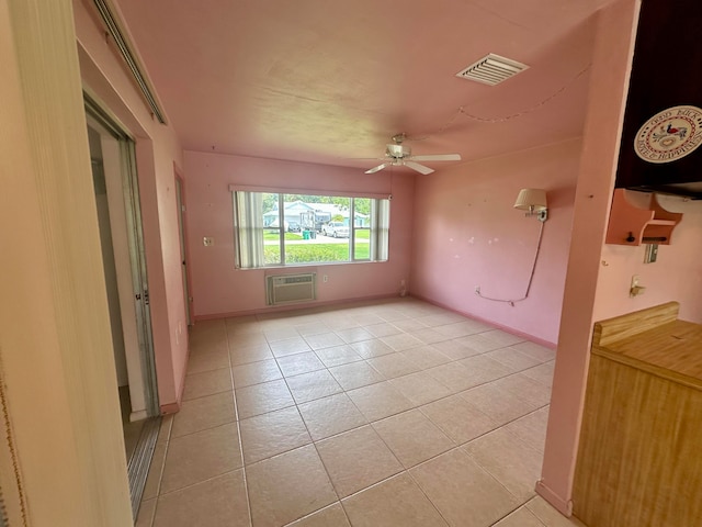 spare room featuring a wall mounted AC, ceiling fan, and light tile patterned floors