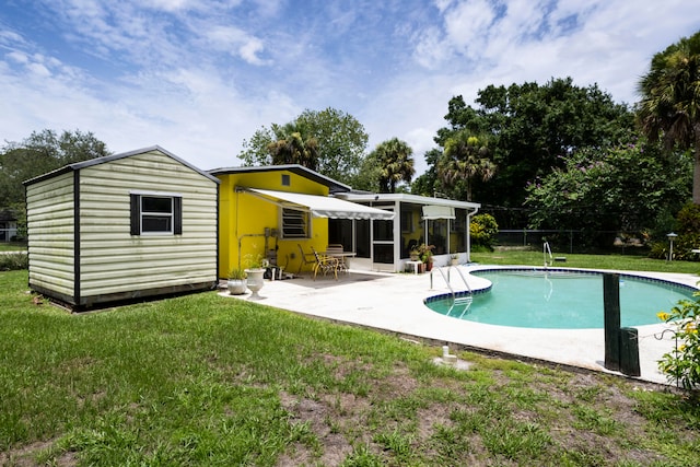 view of swimming pool featuring a patio area, a yard, and an outbuilding