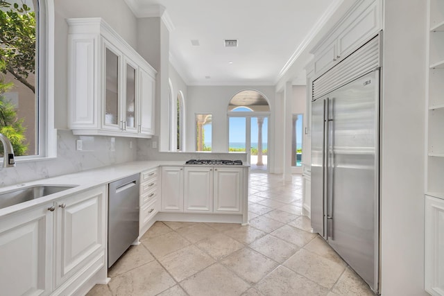 kitchen featuring decorative backsplash, white cabinetry, stainless steel appliances, and ornamental molding