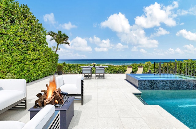 view of pool with an in ground hot tub, a patio, a water view, and a fire pit