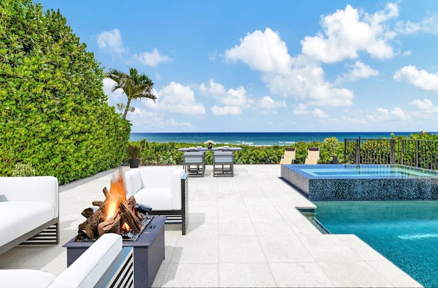 view of patio with a fire pit, an in ground hot tub, and a water view