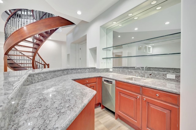 kitchen with light stone countertops, light hardwood / wood-style flooring, stainless steel dishwasher, and sink