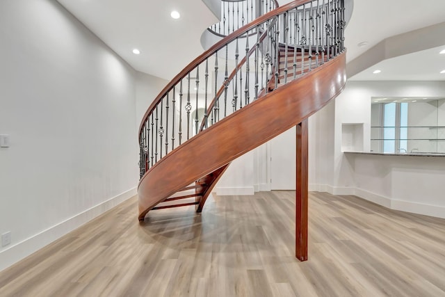 stairway with wood-type flooring and a towering ceiling