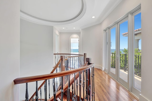 hall with french doors, ornamental molding, a raised ceiling, and light wood-type flooring