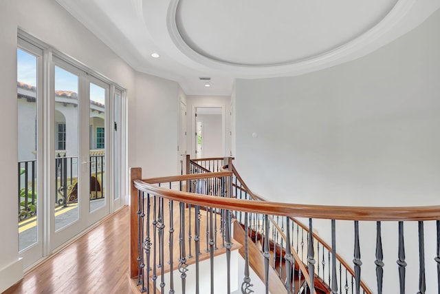 hallway with a tray ceiling and light wood-type flooring