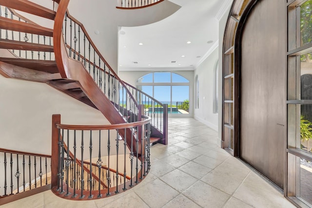 stairway with light tile patterned flooring, ornamental molding, and plenty of natural light