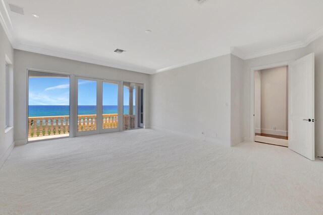 empty room featuring ornamental molding, a water view, and light colored carpet