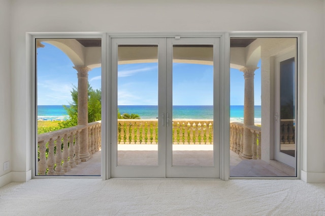 entryway featuring a water view, carpet floors, and a beach view