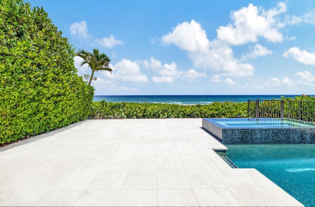 view of pool with an in ground hot tub, a water view, and a patio area