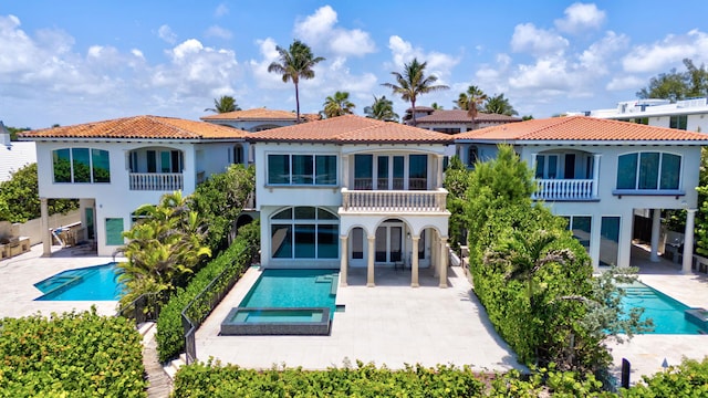 rear view of property featuring a patio area, a balcony, and a pool with hot tub