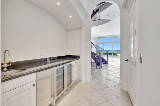 interior space featuring light tile patterned flooring, white cabinetry, beverage cooler, and sink