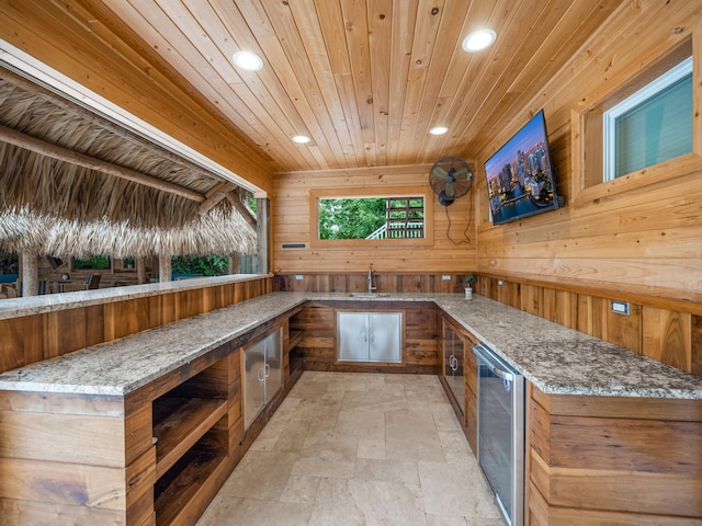 bar with wine cooler, wooden walls, and stone countertops