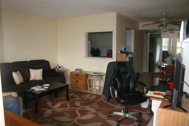 living room featuring ceiling fan and a textured ceiling