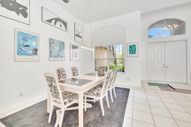 dining room featuring a towering ceiling, light tile patterned flooring, and an inviting chandelier