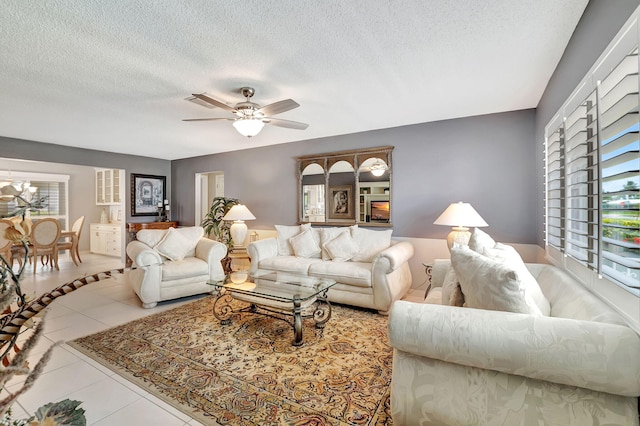 tiled living room featuring ceiling fan and a textured ceiling