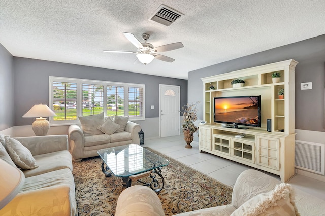 living room with ceiling fan, light tile patterned flooring, and a textured ceiling