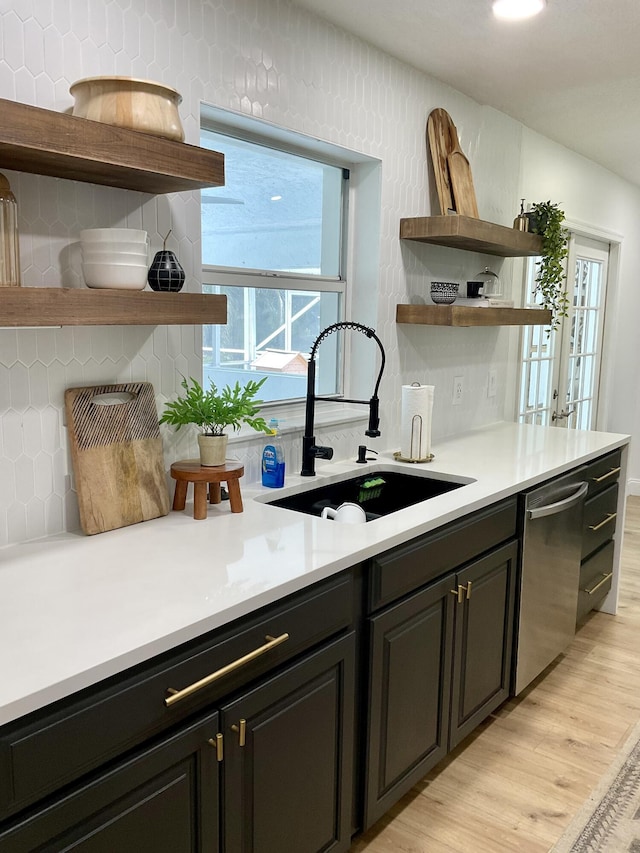 kitchen featuring decorative backsplash, stainless steel dishwasher, a wealth of natural light, sink, and light hardwood / wood-style flooring