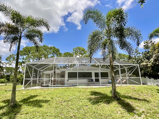 back of property featuring a yard and glass enclosure