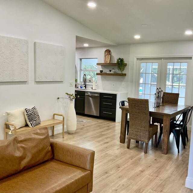 dining space featuring french doors, light hardwood / wood-style flooring, vaulted ceiling, and sink