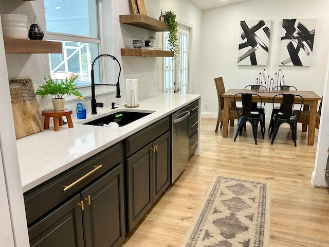 kitchen featuring light wood-type flooring, stainless steel dishwasher, plenty of natural light, and sink