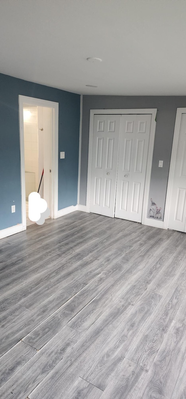 unfurnished bedroom featuring a closet, connected bathroom, and light hardwood / wood-style floors