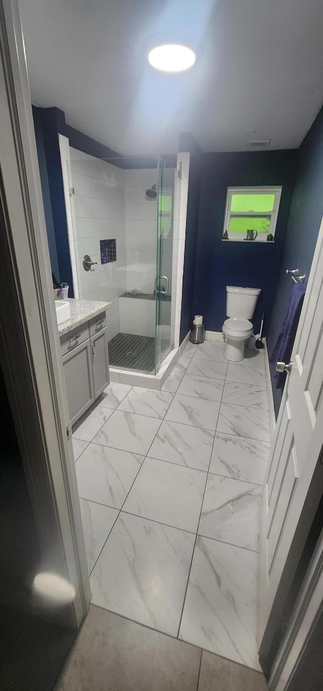 bathroom featuring a shower with shower door, vanity, and toilet