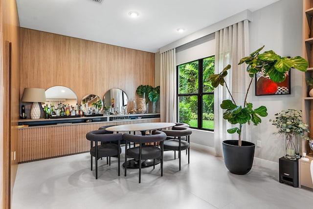 dining room featuring indoor bar and wood walls