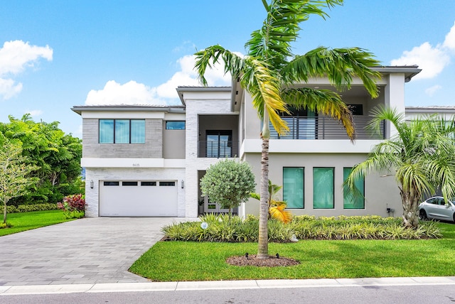 view of front of home featuring a front yard, a balcony, and a garage