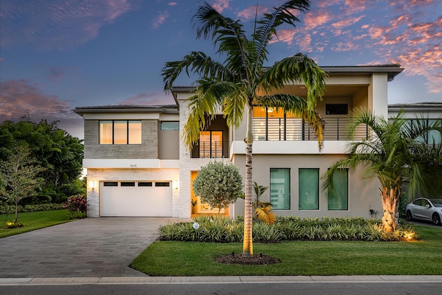 view of front of home with a lawn, a balcony, and a garage