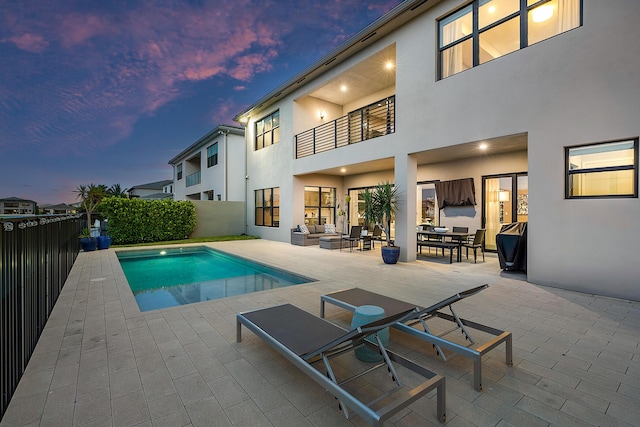 back house at dusk with a patio area and a fenced in pool