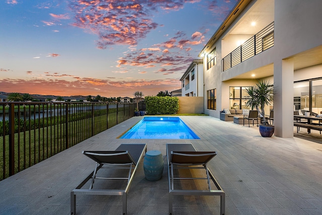 pool at dusk featuring a patio area and outdoor lounge area