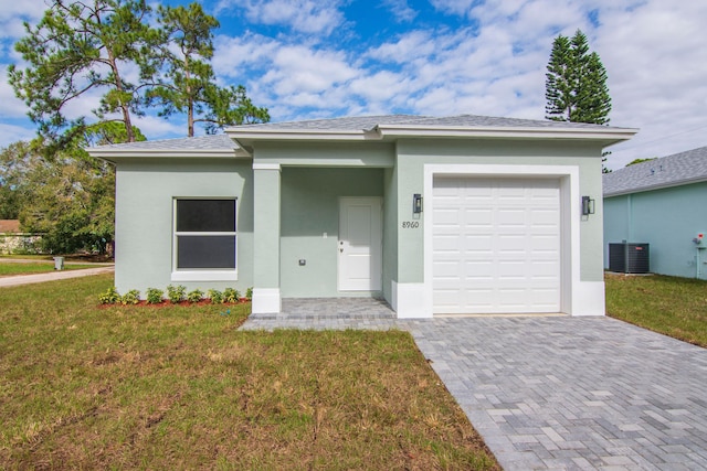 775 11th Ave SW, Vero Beach, FL 32962 - view of front of home with a front yard, an attached garage, central AC unit, decorative driveway, and stucco siding