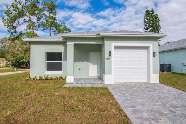 view of front of home with a garage, a front lawn, and central air condition unit